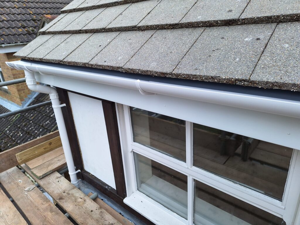 A detached house with new white upvc Fascias, Soffits, guttering and downpipes, above newly installed UPVC double glazed Windows.